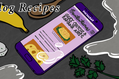 A cell phone sits on a grey marble counter, surrounded by parsley, goat cheese, a banana, a wooden spoon, and some clear fluid that has also gotten on the phone screen. The screens shows a blog called Prententions. The recipe is for goat cheese and banana aspic.