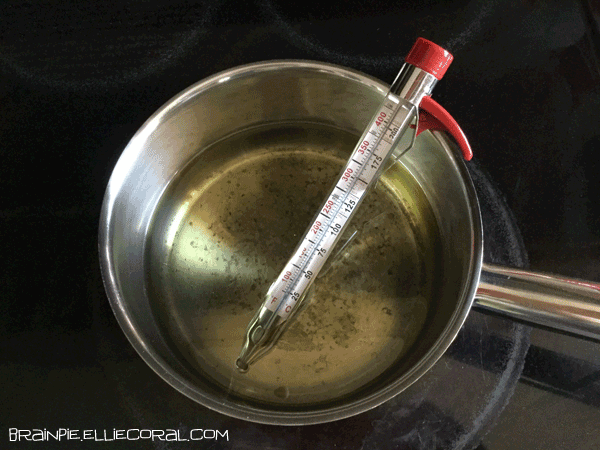 A candy thermometer sitting in a pot of oil.