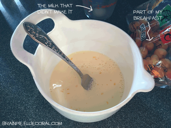 A mixing bowl with egg mixture and a fork sitting in it. Off to the side is a measuring cup with some milk that didn't make it into the recipe, and a bag of cherries that somehow made it into the picture.