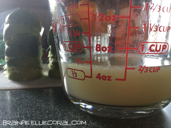 A clear glass measuring cup shows that barely 3/4 cup of lime juice has been collected.