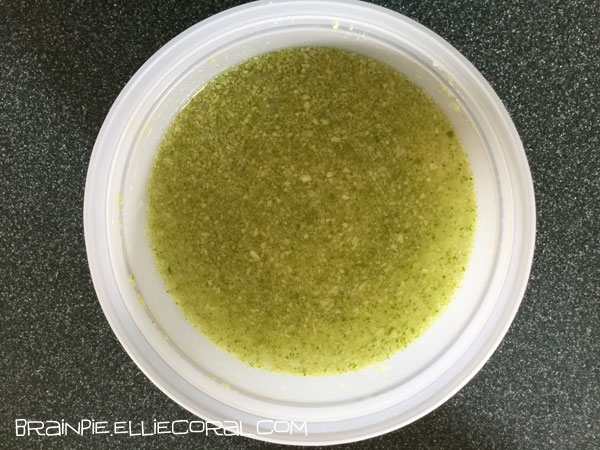 A bowl of lime peel bits clouding a mixture.