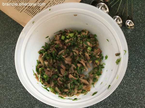 A plastic bowl filled with melted butter, parsley, mushrooms, and green onions.