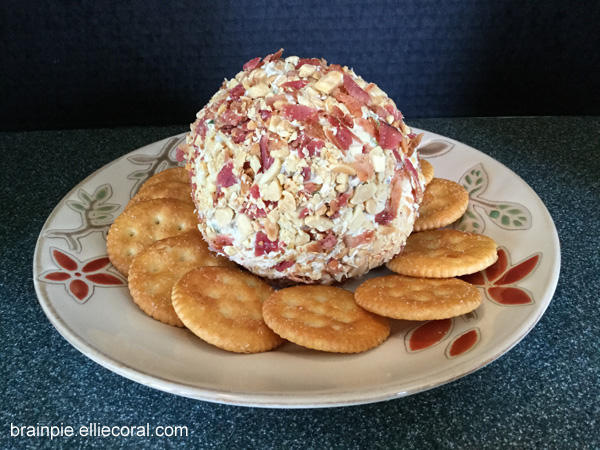 The bacon- and peanut-festooned peanut butter cream cheese ball sits on a place, surrounded by round snack crackers.