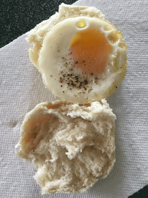 A biscuit sliced in half with a peppered soft boiled egg sitting on one half.