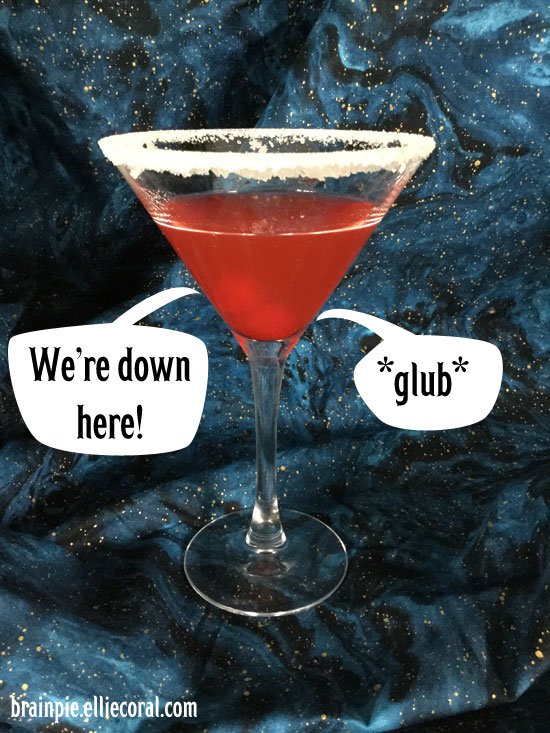 A martini glass rimmed with sugar and filled with red juice. At the bottom of the glass are two cherries yelling, 'We're down here!' '*glub!*'