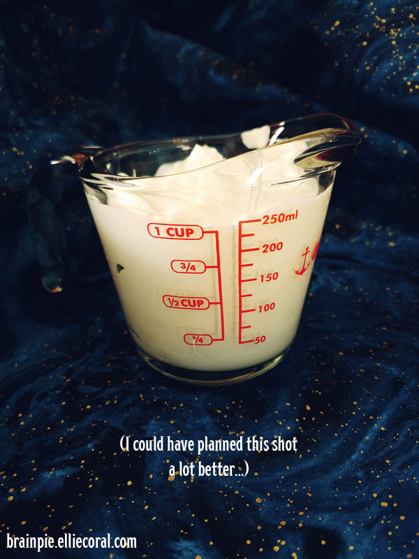 One cup of sour cream in a glass measuring cup. The photo is somewhat dark, especially in the background. The text reads, I could have planned this shot a lot better...